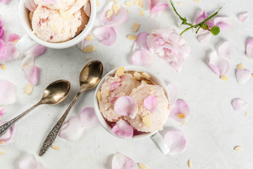Summer refreshing desserts. Vegan diet food. Ice cream with rose petals and slices of almond, in white serving bowls, on a white concrete table. Copy space