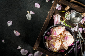 Summer refreshing desserts. Vegan diet food. Ice cream with rose petals and slices of almonds, on wooden old tray, on black stone table. With spoon for ice cream and ingredients. Copy space top view