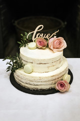 Obraz na płótnie Canvas Beautiful wedding cake with cream With text Love on top pink flowers roses