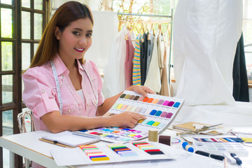 A young asian woman 20s is choosing the color of fabric for her new collection with full of creativity