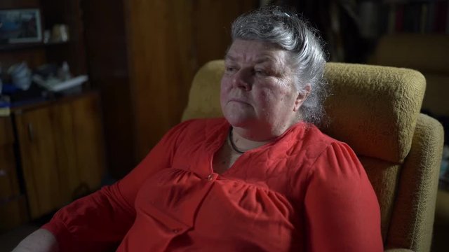 70 year old elderly woman in armchair watching TV