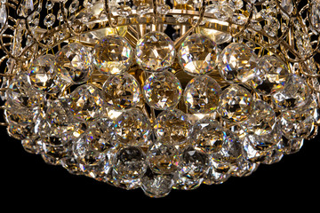 Large crystal chandelier close-up isolated on black background.