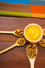 Wooden spoons with toasted corn grains, known as tostado in south america, spread around bowl containing yellow salsa, seen from above