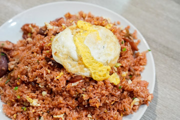 Fried rice with pork and fried egg on a plate and wooden table. Thai food