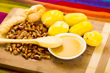 Traditional ecuadorian dish, potatoes, tostados and bowl of salsa with wooden spoon, seen from above