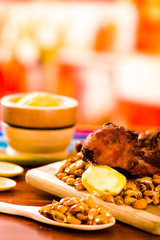 Closeup traditional ecuadorian dish, grilled guinea pig spread out onto wooden board, tostados and salsa on the side, seen from above
