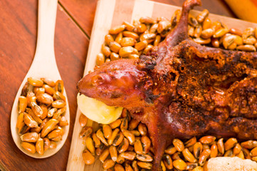 Closeup traditional ecuadorian dish, grilled guinea pig spread out onto wooden board, tostados and salsa on the side, seen from above