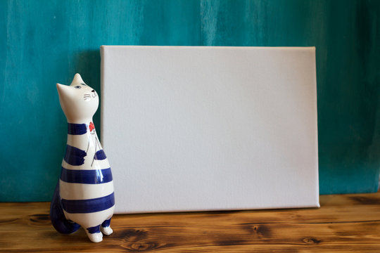 Mock Up Poster. White Empty Canvas And Cute Ceramic Statue Of A Cat.