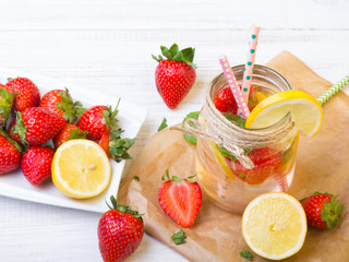 Mineral  water with fresh strawberries, lemon  and mint in jar on a white wooden background, copy space
