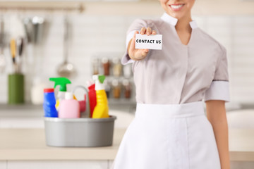 Young chambermaid with business card in kitchen