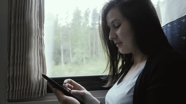 Woman Using Tablet PC Next to Window in Moving Train, Travel Concept