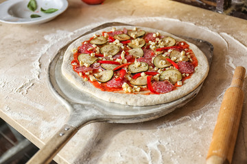 Tasty pizza on shovel and kitchen table