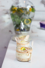 Lemon mousse jars on dessert buffet table at a rustic restaurant with lemonade pitcher in the background.