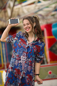 Excited young woman is dancing and singing to the music on her phone