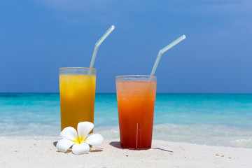 Cocktails in glass on white sandy beach