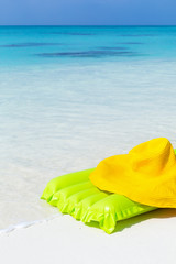 Green airbed ans hat on beach