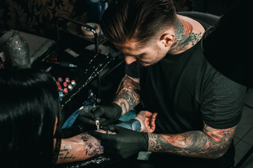 Professional tattoo artist makes a tattoo on a young girl's hand - 158797702