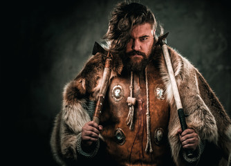 Viking with cold weapon in a traditional warrior clothes