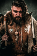 Viking with cold weapon in a traditional warrior clothes