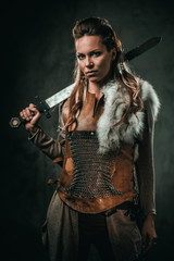 Viking woman with cold weapon in a traditional warrior clothes