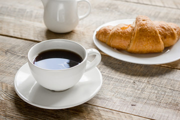Business breakfast in office with coffee, milk and croissant on wooden table background