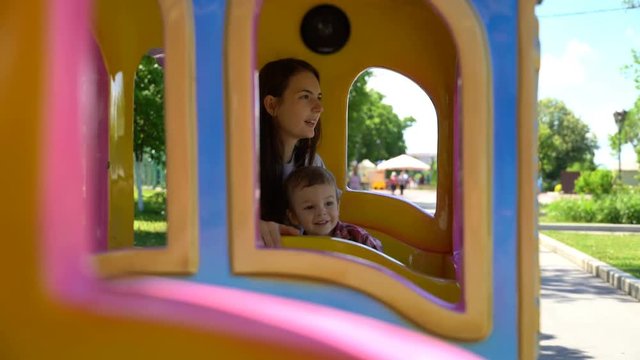 Son with mom riding a child's train.