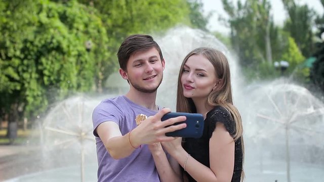 Positive young couple having fun and doing selfie on the street