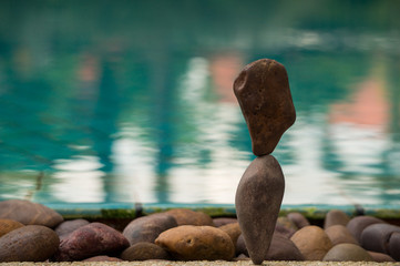 Rock balancing with a pool in the background
