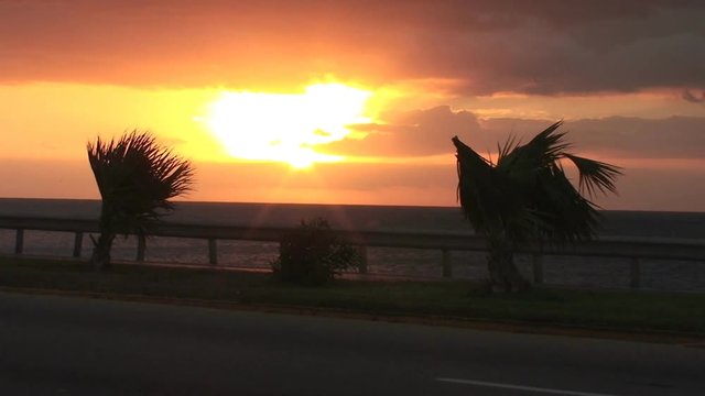 Cars and cyclists pass on oceanside highway in Varadero, Cuba at sunset