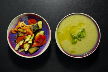 grilled vegetables and courgette cream soup, healthy vegetarian meal on black background