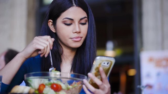 Asian Woman Texting On Smartphone And Eating Salad In Restaurant