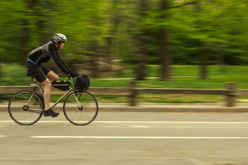 Young man and his bike in the central park, panning