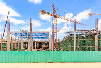 Construction site. Construction cranes and high-rise building under construction against blue sky