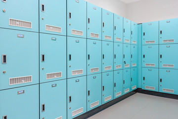 Stack of green metal school lockers with combination locks and doors shut as background
