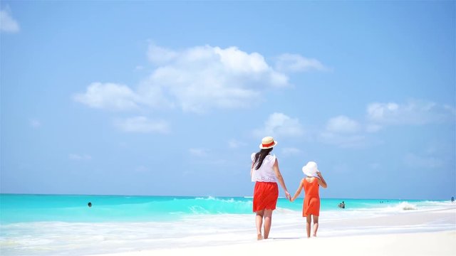 Little adorable girl and young mother at tropical beach. Family of two have a lot of fun during summer vacation