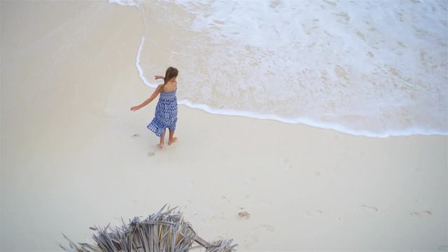 Adorable little girl having a lot of fun in shallow water.View from above of a deserted beach with turquoise water