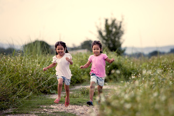 Two asian little girls having fun and running together in the park in vintage color tone