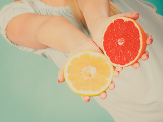Halfs of yellow red grapefruit citrus fruit in human hands