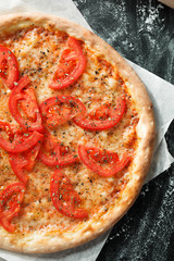 Delicious pizza with tomato on dark background