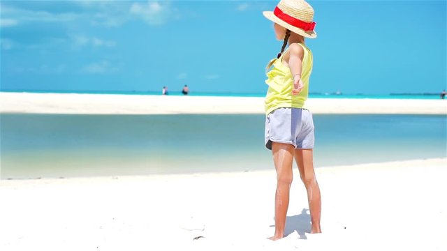 Little adorable girl in hat on white tropical beach. SLOW MOTION.