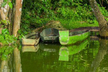 Fototapeta na wymiar Old green fishing wooden boat in a calm lake water