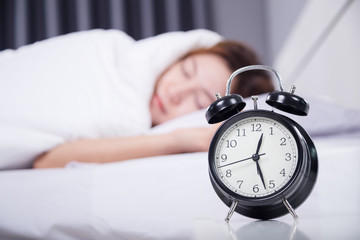 clock with woman sleeping under white blanket on bed