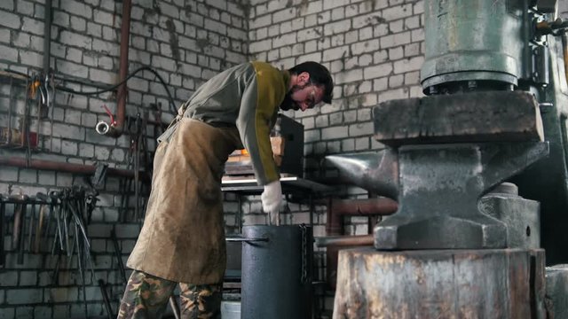 Blacksmith chills the detail in a barrel of engine oil
