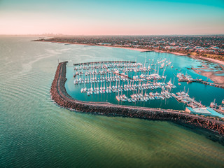 Aerial panoramic view of moored yachts at Sandringham Marina and Melbourne coastline at sunset....