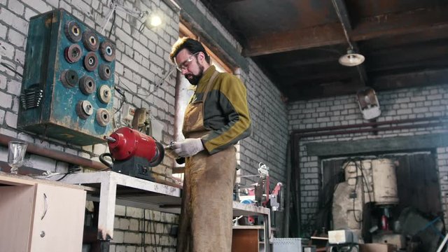 In the forge, a men sharpens a steel details