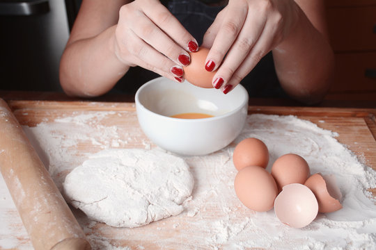 Woman breaking an egg into bowl.
