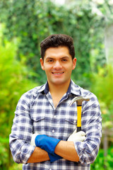 Atractive man wearing casual clothes holding a hammer in a forest background