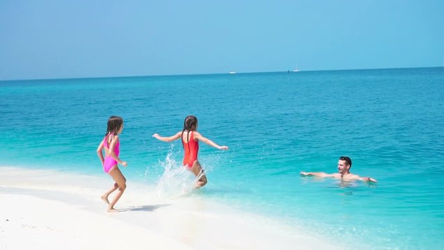 Happy family at tropical beach have fun. Father and little kids enjoy time together swimming in the sa. SLOW MOTION