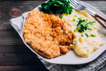 Homemade Sliced Wiener Chicken Schnitzel with herb and mashed potatoes on plate on wooden table...