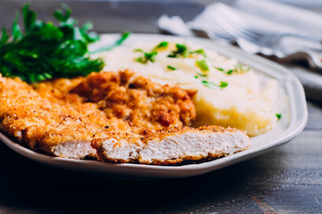 Homemade Sliced Wiener Chicken Schnitzel with herb and mashed potatoes on plate on wooden table background. Healthy food.